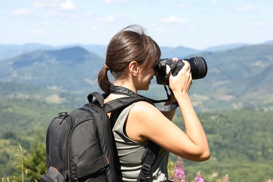 Photographer with backpack and camera taking picture of beautiful mountains