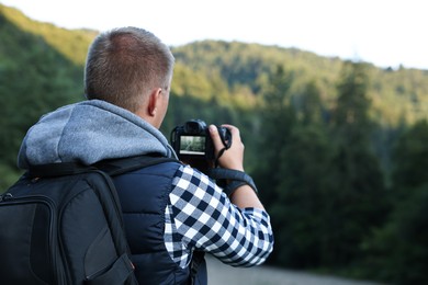 Photo of Photographer with backpack and camera taking picture of beautiful mountains