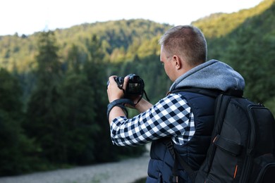 Photo of Photographer with backpack and camera taking picture of beautiful mountains