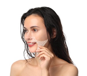 Smiling woman peeling off face mask on white background