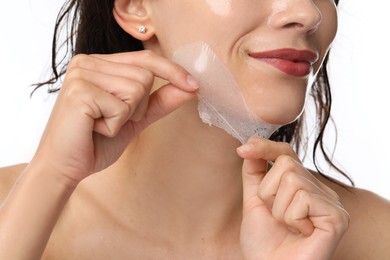 Photo of Woman peeling off face mask on white background, closeup