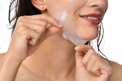 Woman peeling off face mask on white background, closeup