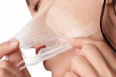 Photo of Woman peeling off face mask on white background, closeup