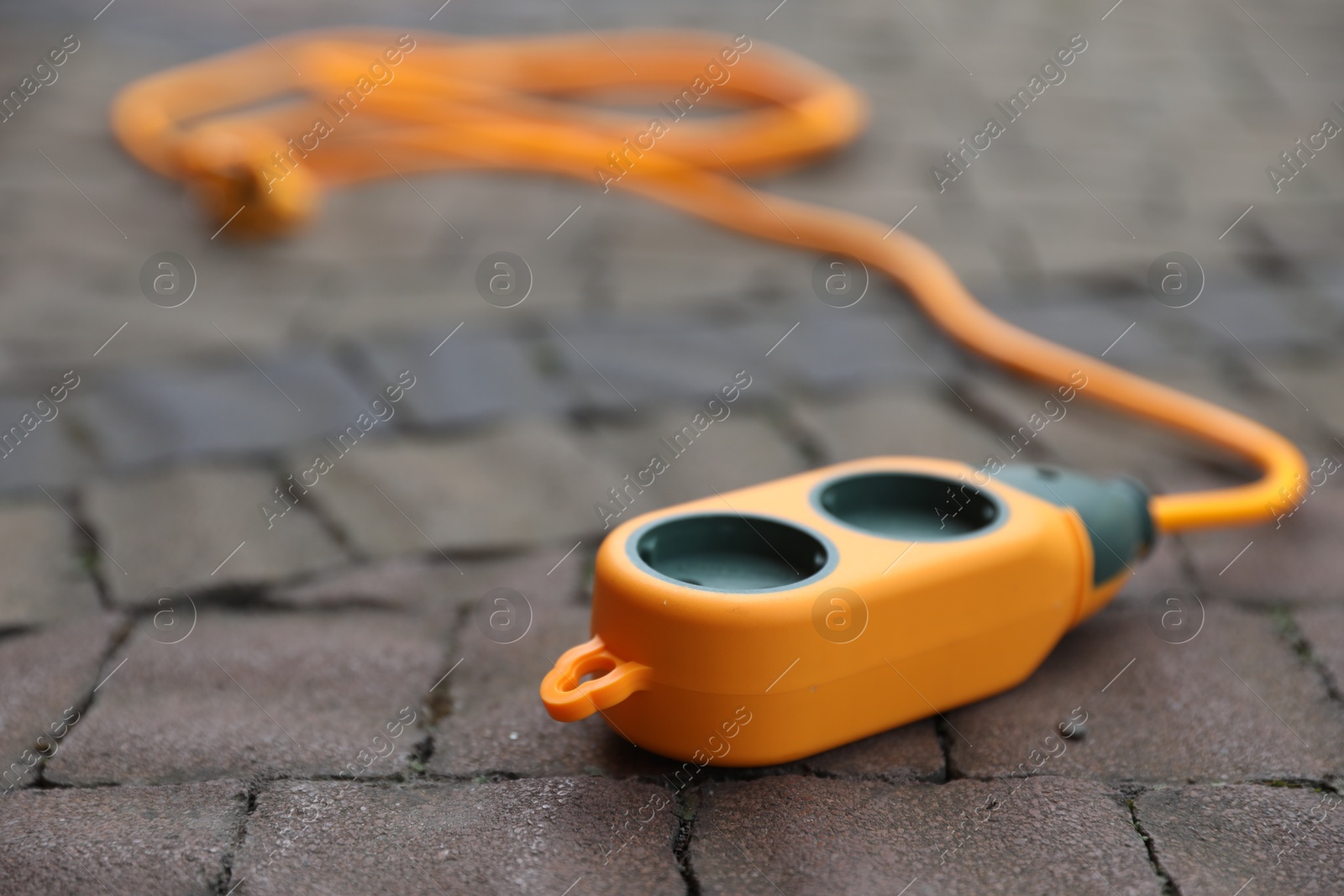 Photo of One extension cord on paved pathway outdoors, closeup