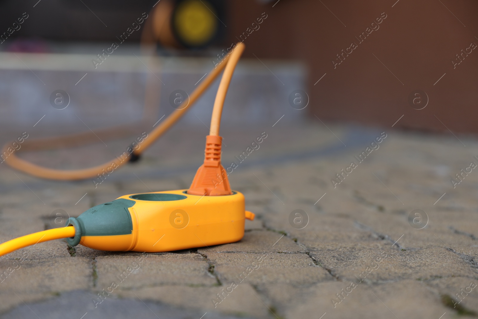 Photo of Extension cord on paved pathway outdoors, closeup. Space for text