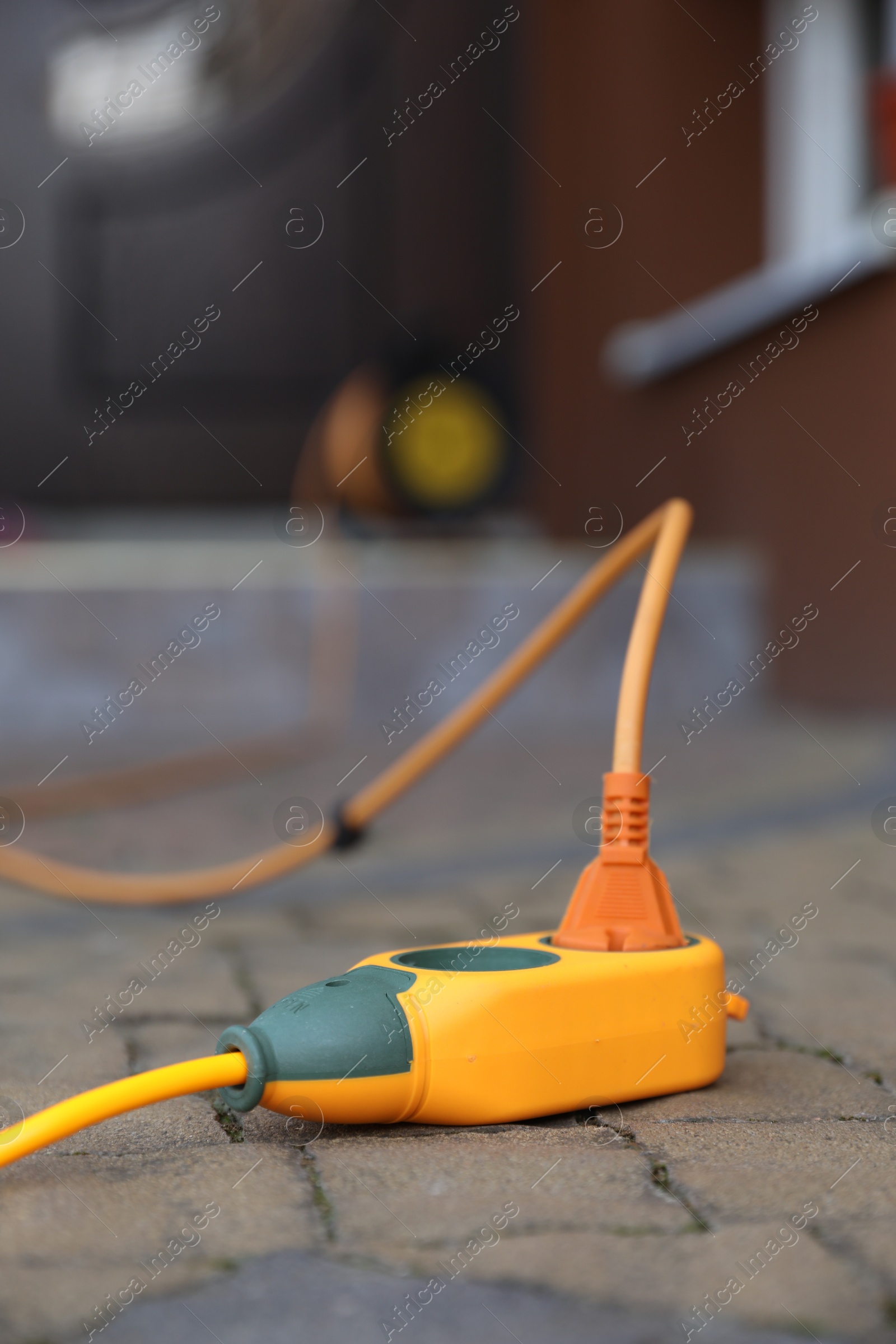 Photo of Orange extension cord on paved pathway outdoors