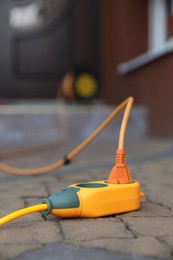 Orange extension cord on paved pathway outdoors