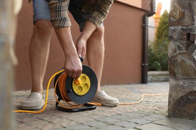 Photo of Man with extension cord reel outdoors, closeup