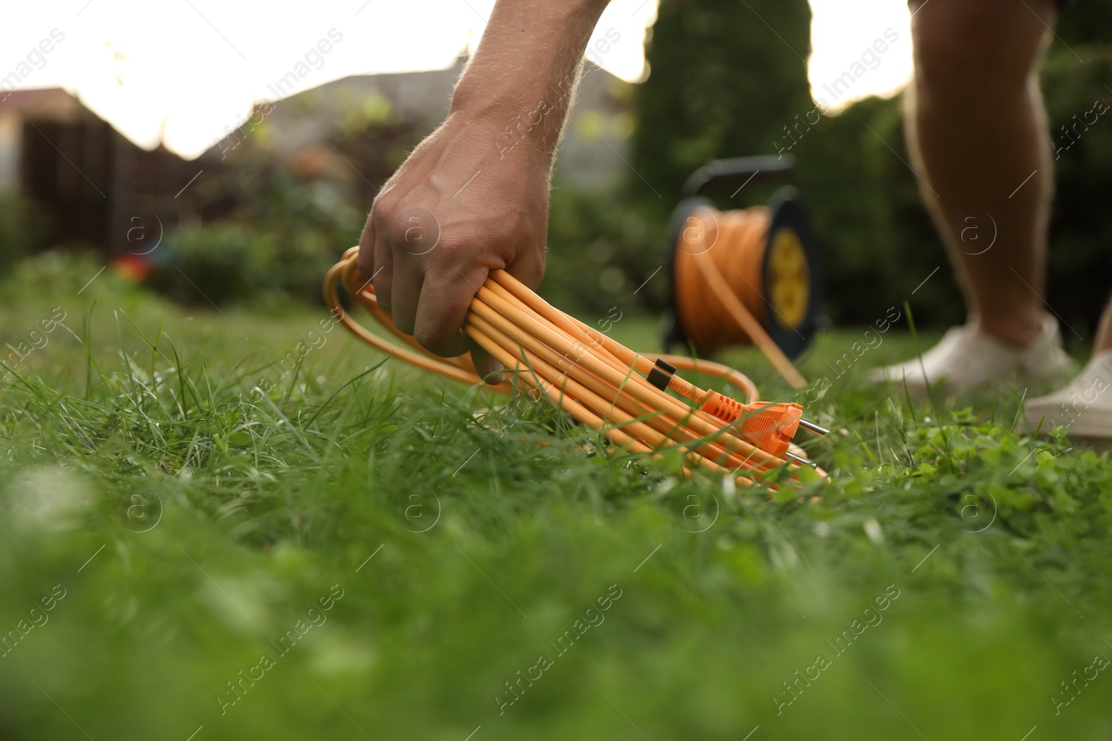 Photo of Man with extension cord on green grass outdoors, closeup