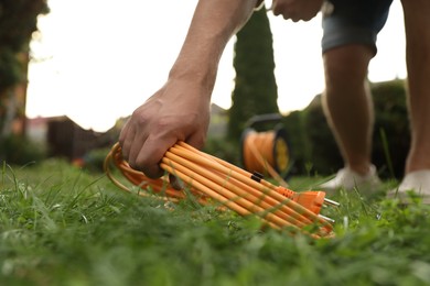 Photo of Man with extension cord on green grass outdoors, closeup