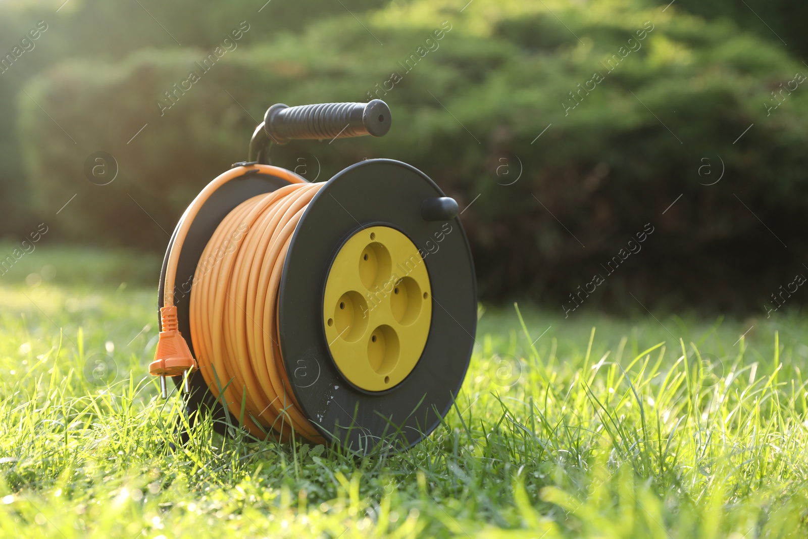 Photo of One extension cord reel on green grass outdoors, space for text