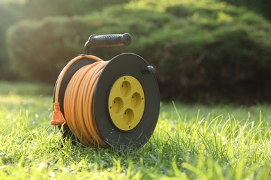 One extension cord reel on green grass outdoors, space for text