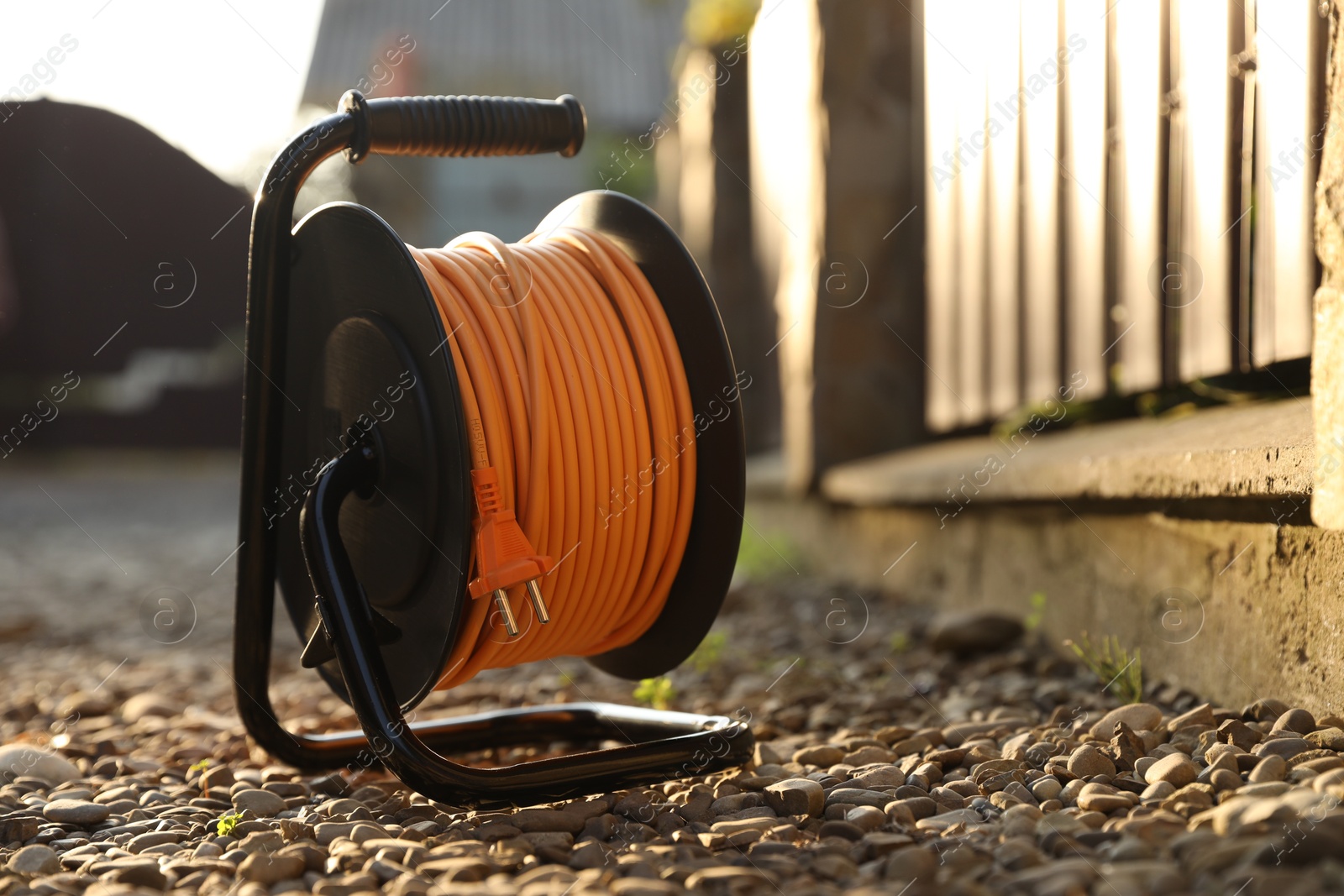 Photo of One extension cord reel on stones outdoors, space for text