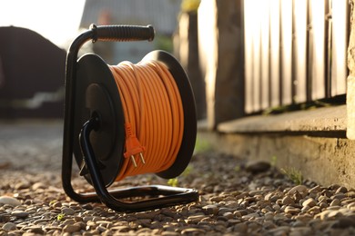 Photo of One extension cord reel on stones outdoors, space for text