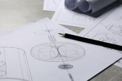 Different engineering drawings and pencil on gray textured table, closeup