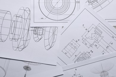 Different engineering drawings on gray textured table, top view