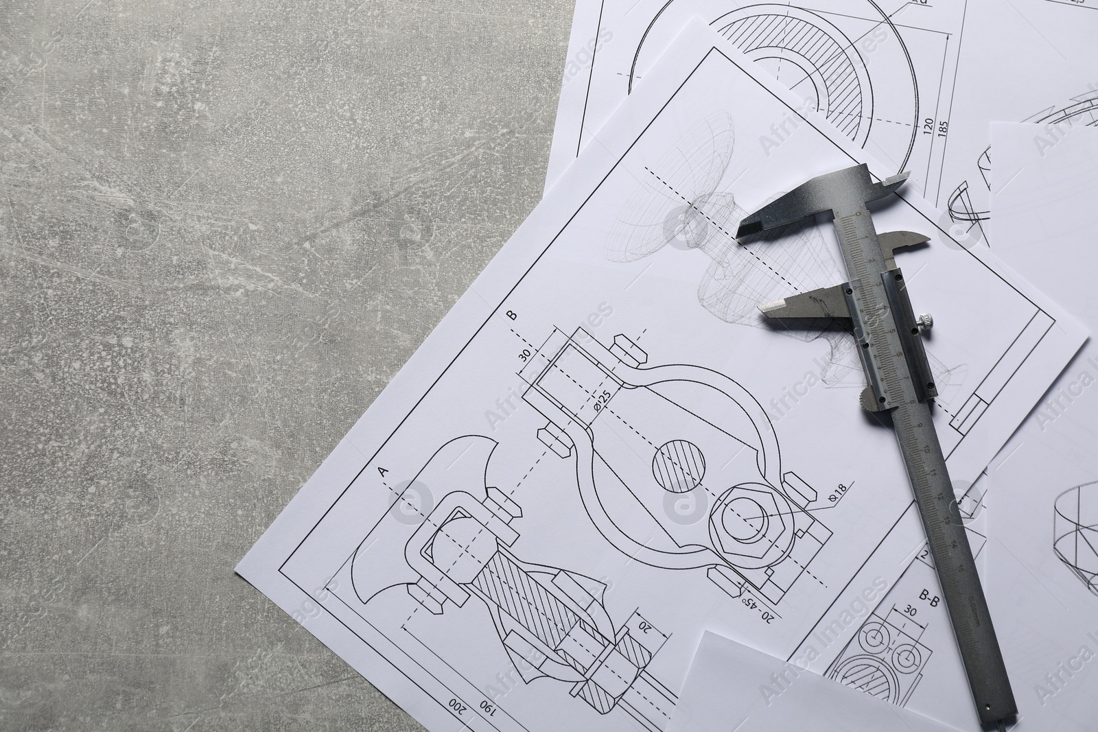 Photo of Different engineering drawings and vernier caliper on gray textured table, top view. Space for text