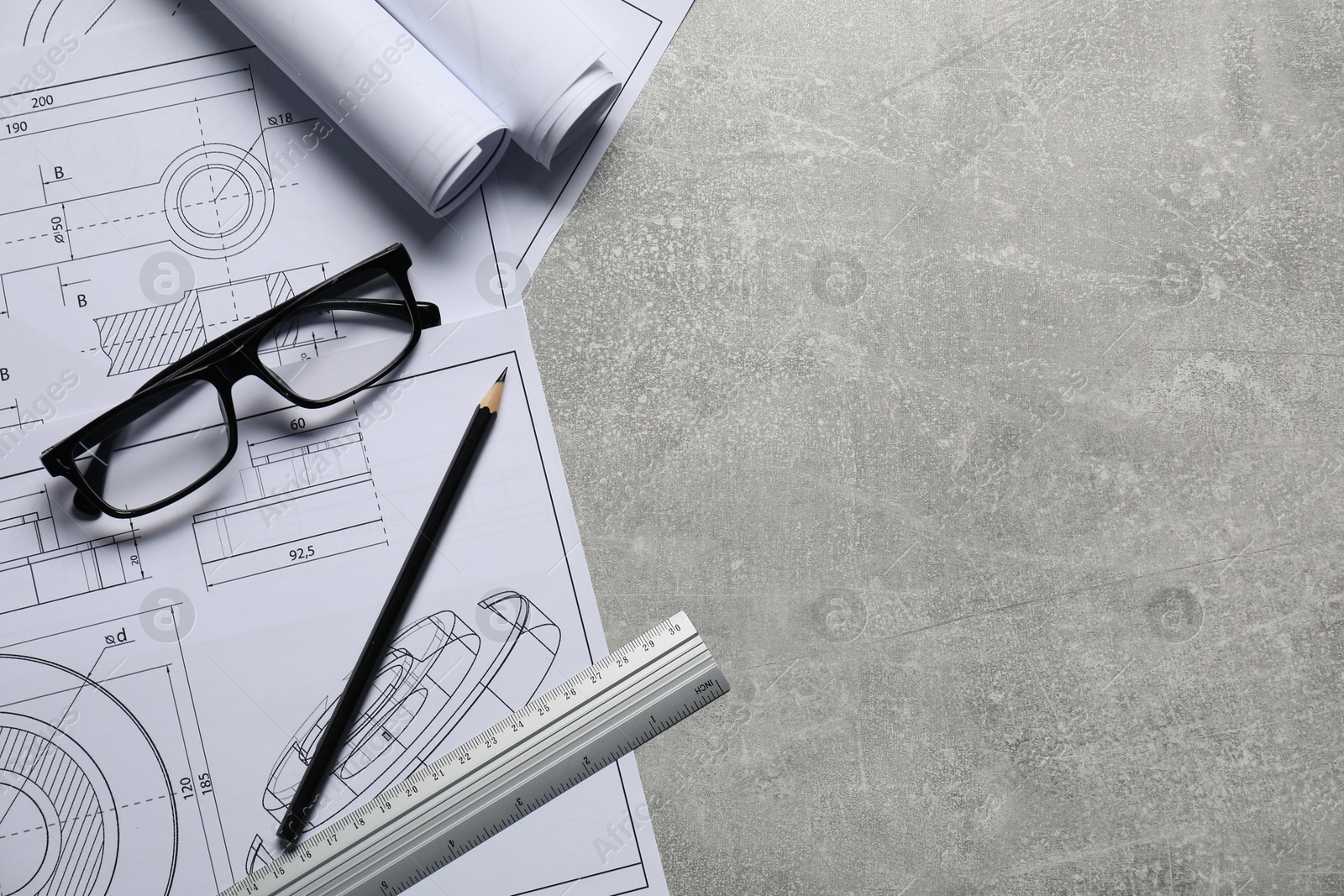 Photo of Different engineering drawings, ruler, pencil and glasses on gray textured table, top view. Space for text