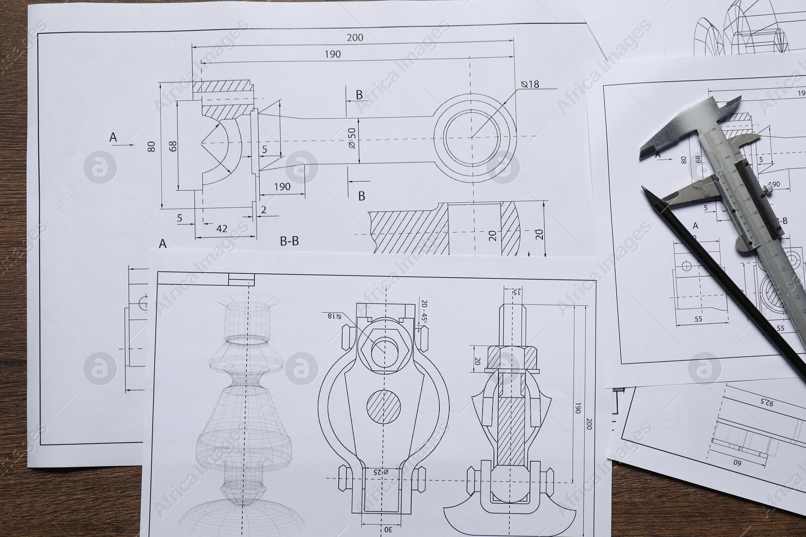 Photo of Different engineering drawings, vernier caliper and pencil on wooden table, top view