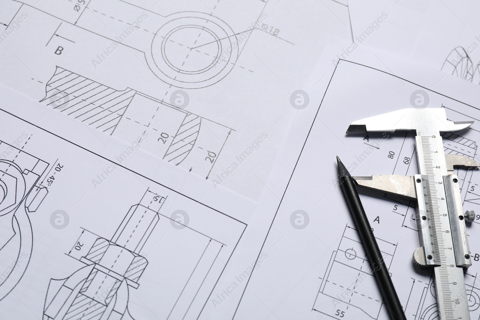 Photo of Different engineering drawings, vernier caliper and pencil, above view