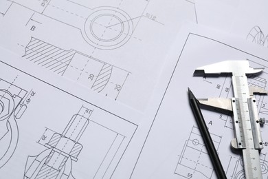 Photo of Different engineering drawings, vernier caliper and pencil, above view