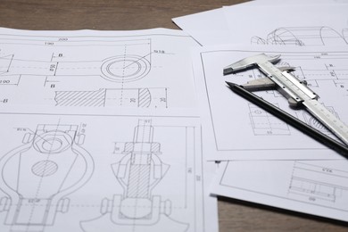 Photo of Different engineering drawings, vernier caliper and pencil on table, closeup