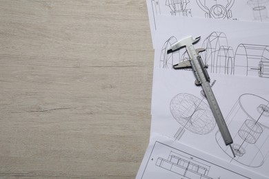 Photo of Different engineering drawings and vernier caliper on wooden table, top view. Space for text