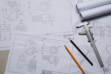 Different engineering drawings, vernier caliper and pencils on table, top view