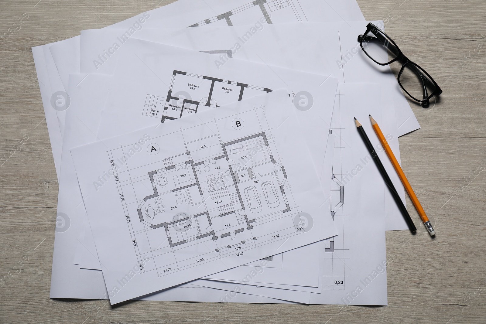 Photo of Different architectural drawings, glasses and pencils on wooden table, top view