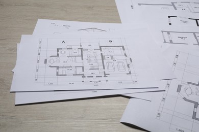 Different architectural drawings on wooden table, closeup