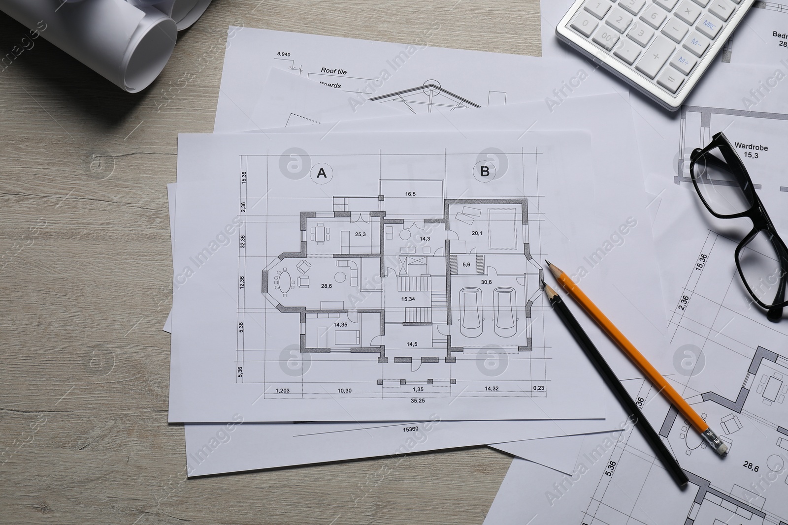 Photo of Different architectural drawings, calculator, glasses and pencils on wooden table, top view