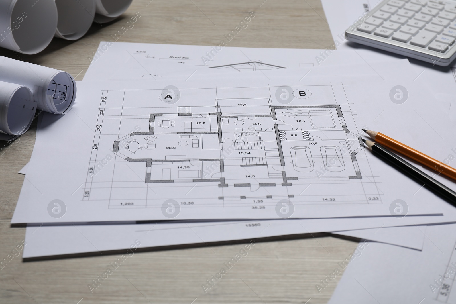 Photo of Different architectural drawings, calculator and pencils on wooden table, closeup