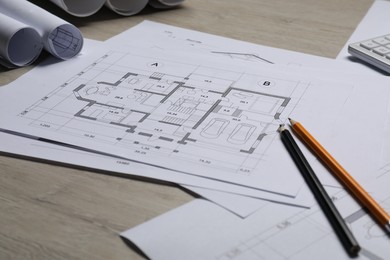 Different architectural drawings and pencils on wooden table, closeup