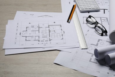 Different architectural drawings and tools on wooden table, closeup