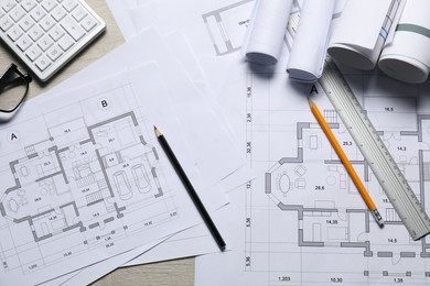 Photo of Different architectural drawings and tools on wooden table, flat lay