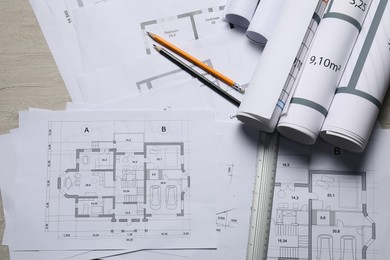 Different architectural drawings, ruler and pencils on wooden table, top view