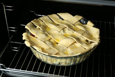 Photo of Baking dish with raw homemade apple pie in oven, closeup