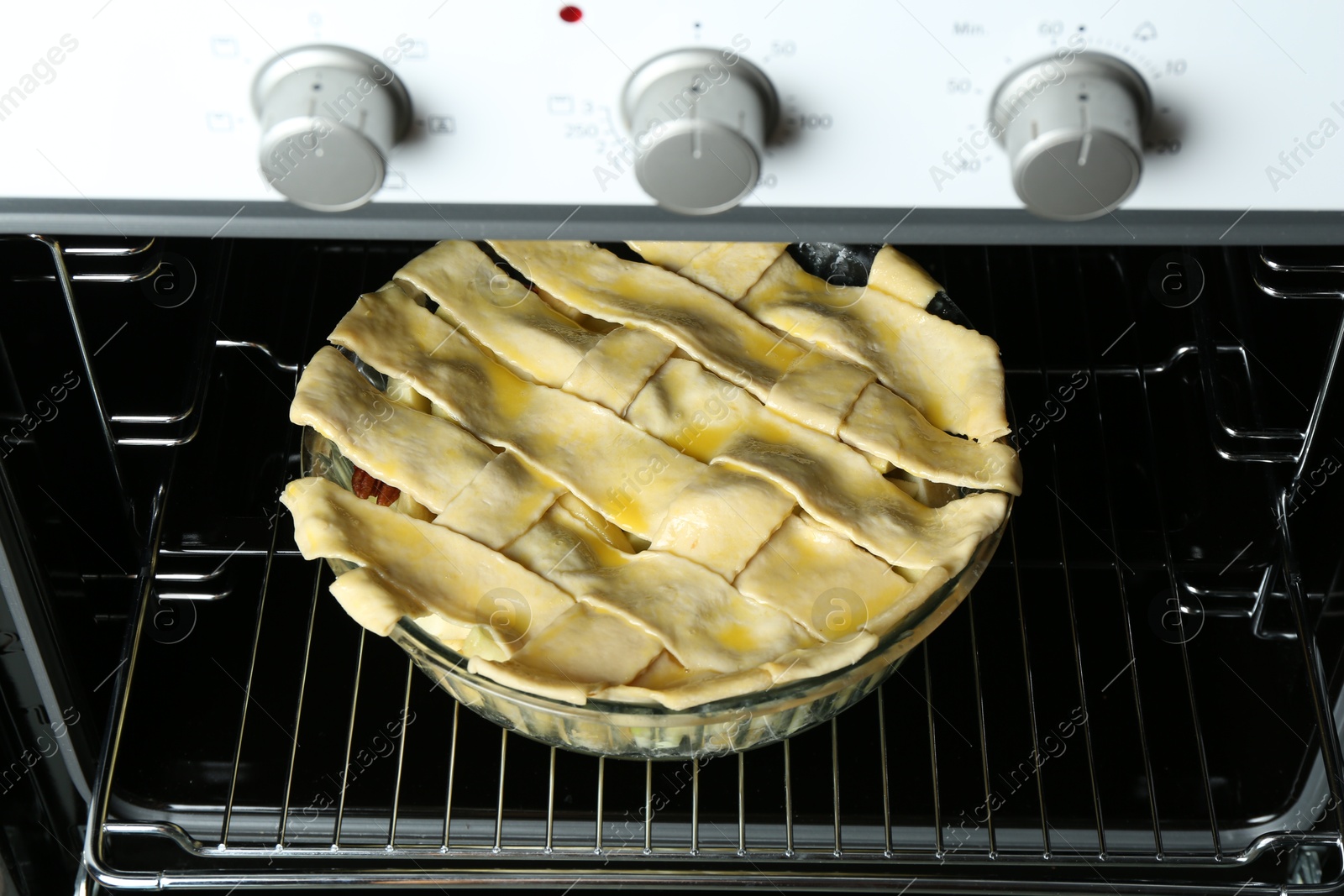 Photo of Baking dish with raw homemade apple pie in oven