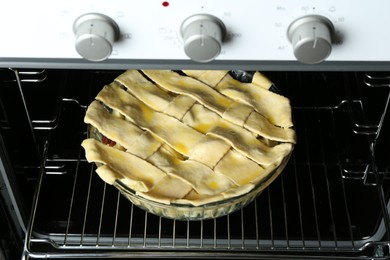 Photo of Baking dish with raw homemade apple pie in oven