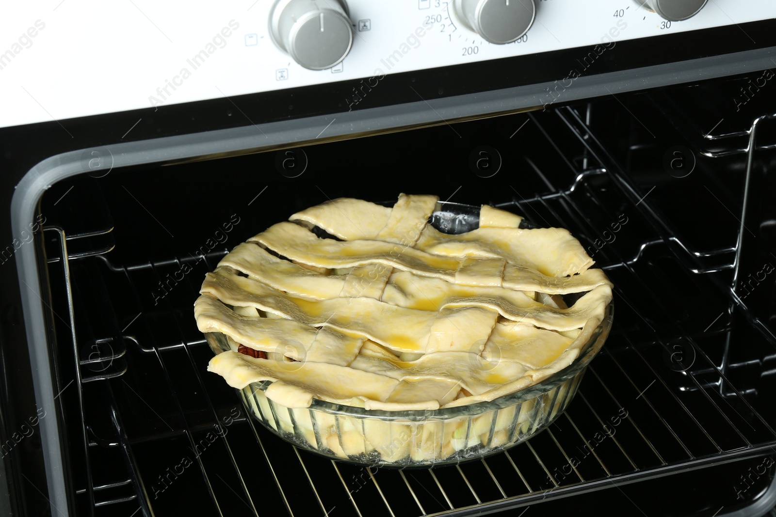 Photo of Baking dish with raw homemade apple pie in oven