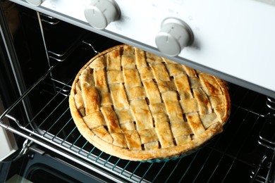 Photo of Baking dish with homemade apple pie in oven, closeup