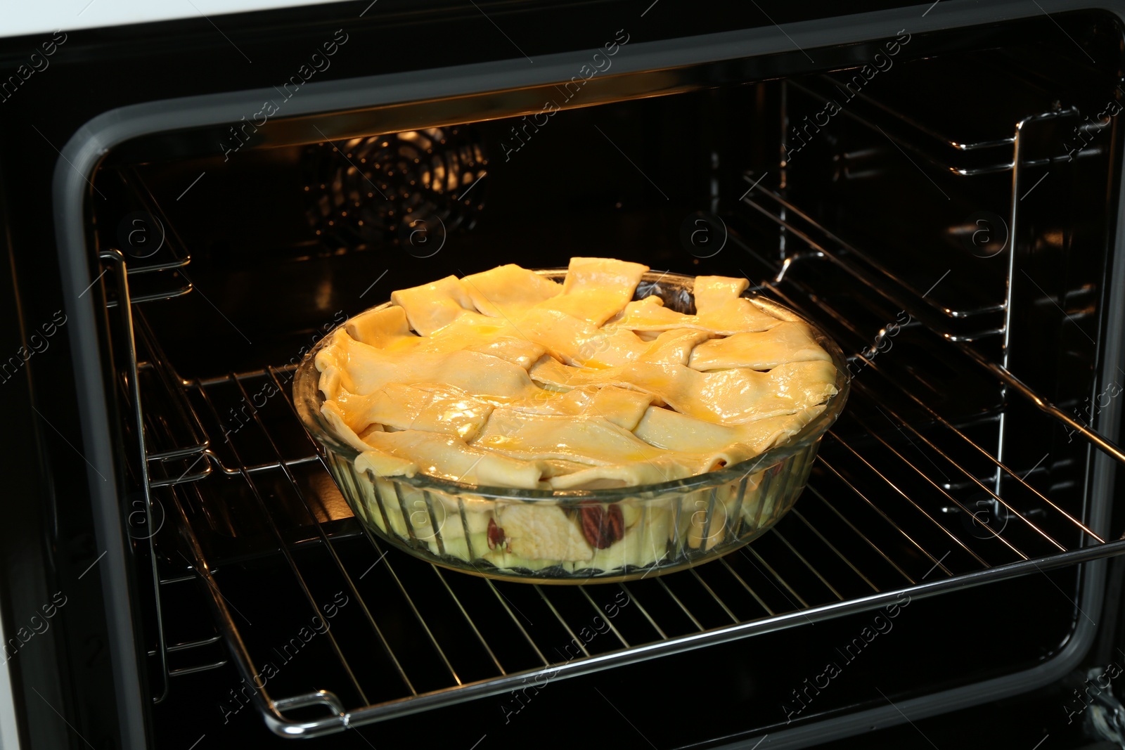 Photo of Baking dish with raw homemade apple pie in oven