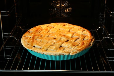 Baking dish with homemade apple pie in oven, closeup