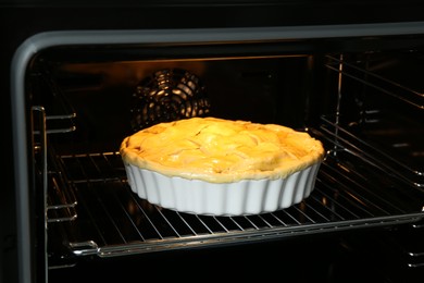 Photo of Baking dish with raw homemade apple pie in oven