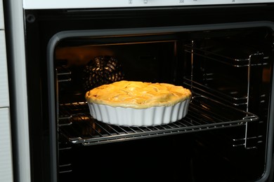 Photo of Baking dish with raw homemade apple pie in oven