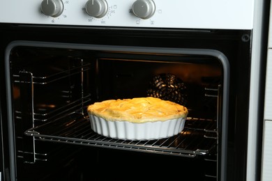 Photo of Baking dish with raw homemade apple pie in oven