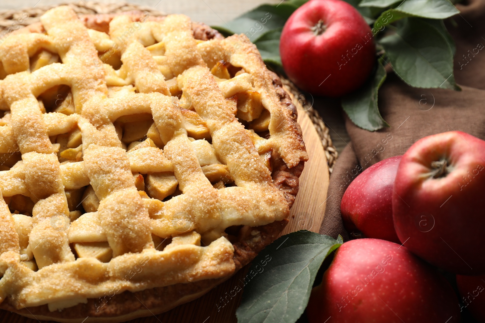 Photo of Tasty homemade apple pie, fruits and leaves on table, closeup