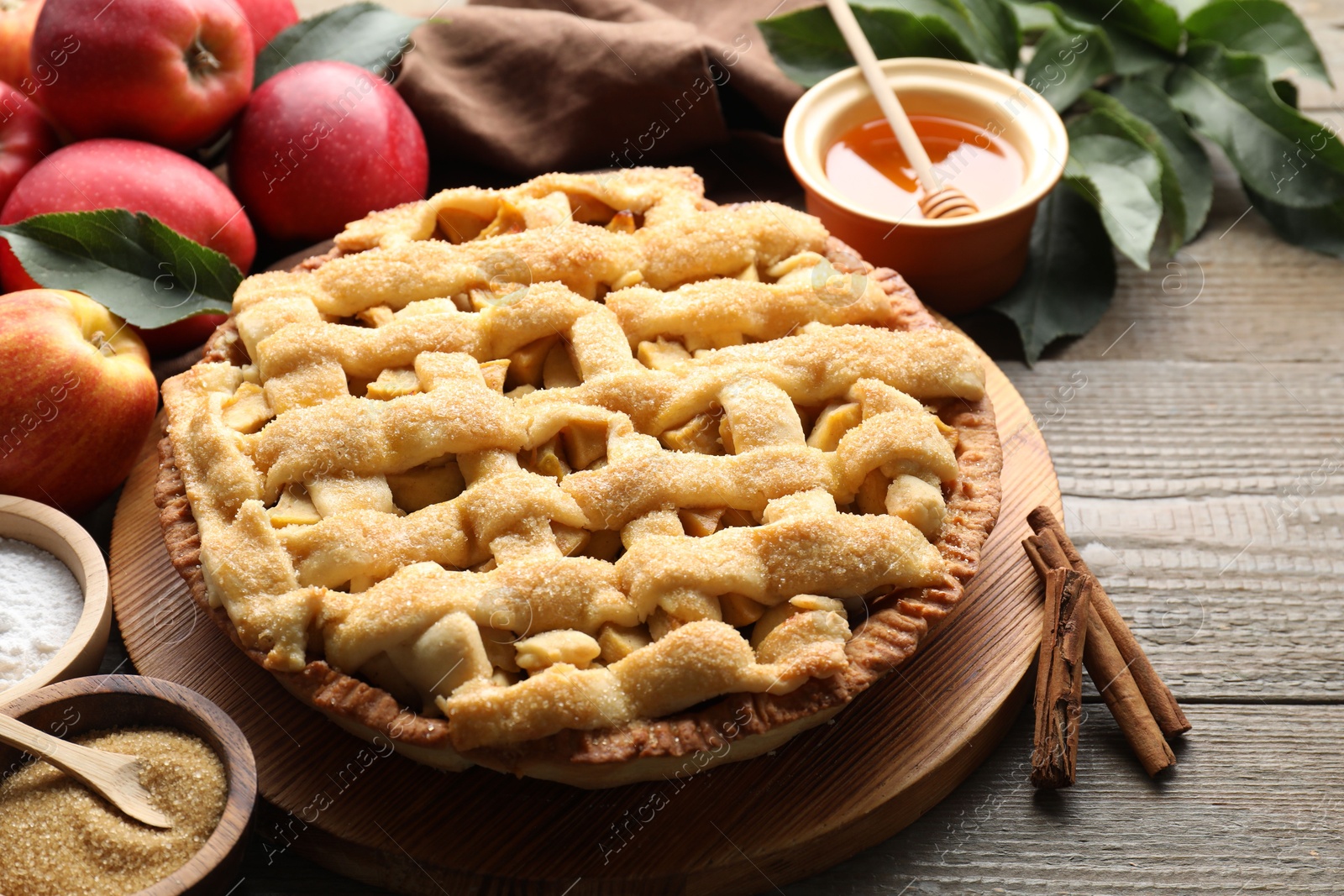 Photo of Tasty homemade apple pie and ingredients on wooden table, closeup