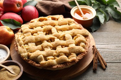 Tasty homemade apple pie and ingredients on wooden table, closeup