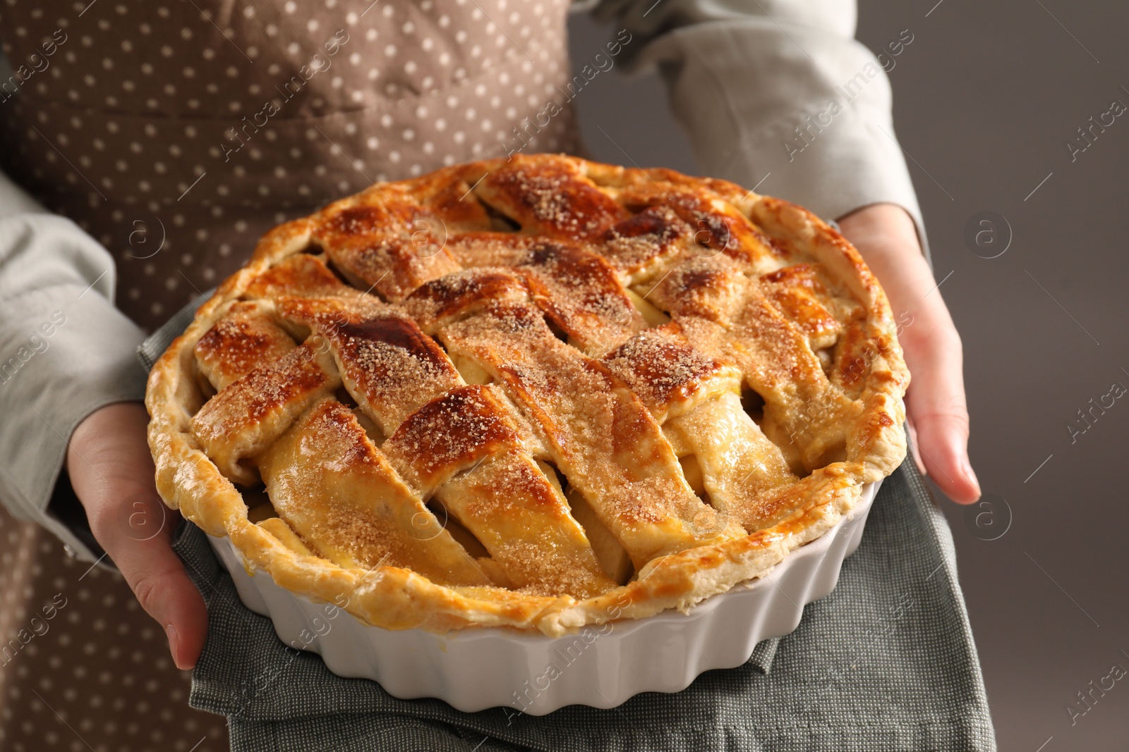 Photo of Woman holding tasty homemade apple pie on dark background, closeup